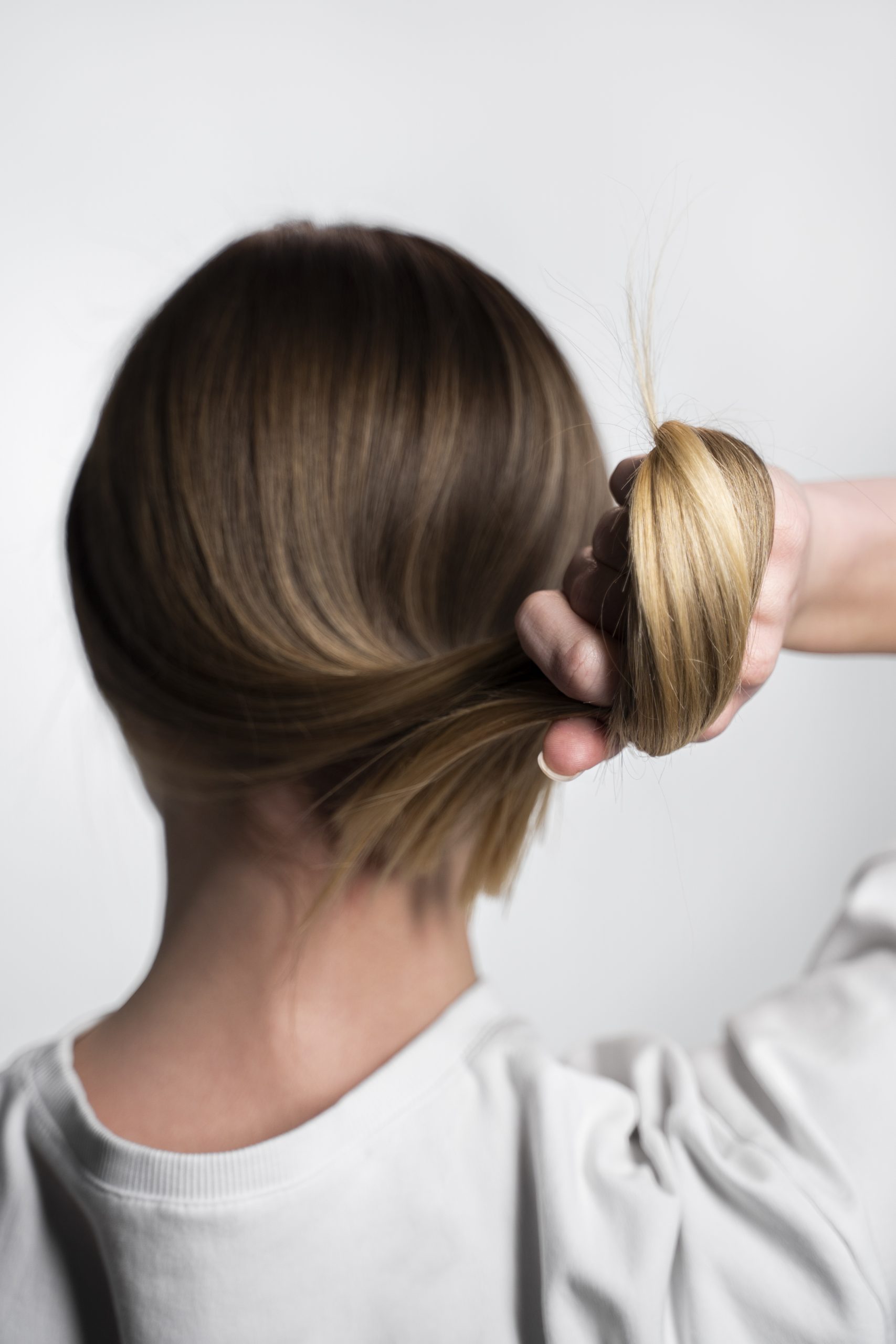 Tüp mide sonrası saç dökülmesiyle incelenen saç tutamını arkadan gösteren kadın